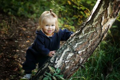 Portrait of smiling boy on tree trunk