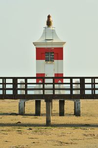 Lighthouse by building against clear sky
