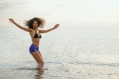 Woman with arms raised standing in sea