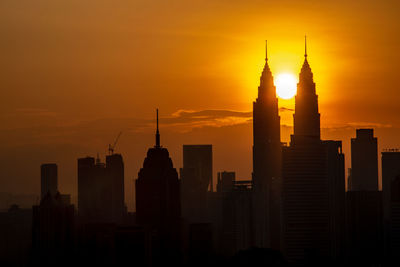 Silhouette of buildings in city during sunset