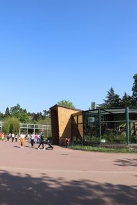 People on road against clear blue sky