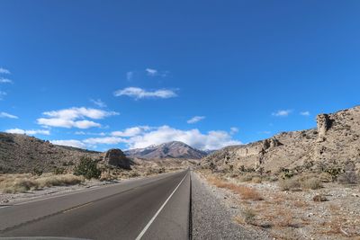 Road amidst mountains against blue sky