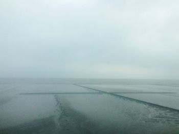 Scenic view of salt flats against sky during foggy weather