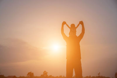 Silhouette man standing by heart shape against sky during sunset