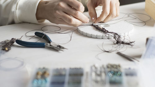 Close-up of woman working with thread on table