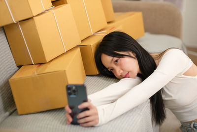 Portrait of young woman using mobile phone while sitting on bed at home