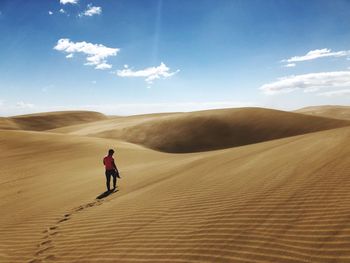 Rear view of man standing at desert against sky