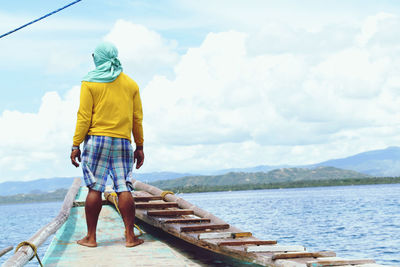 Rear view of man on lake against sky