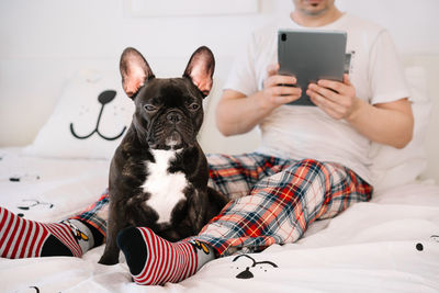 Dog owner and french bulldog relaxing on bed at home