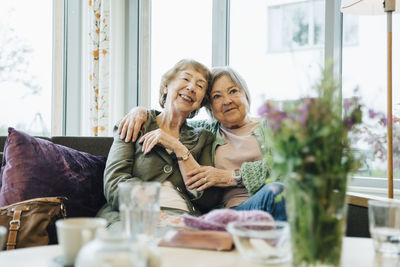 Portrait of happy friends sitting on table