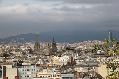 View of cityscape against cloudy sky