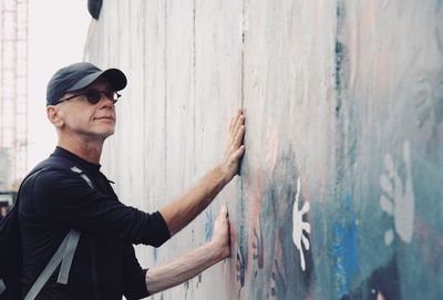 Side view of mature man touching graffiti wall