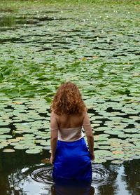 Rear view of woman standing by lake