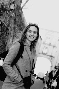 Portrait of young woman standing against wall