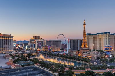 Illuminated buildings in city against sky during sunset