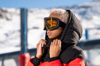 Una mujer afroamericana con gafas de pie en una montaña nevada durante el invierno