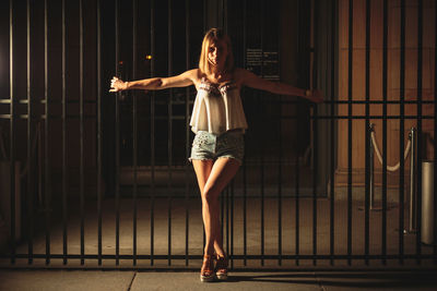 Young woman standing against gate