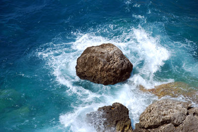 High angle view of waves breaking on rocks