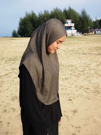 Girl wearing hijab while standing at beach