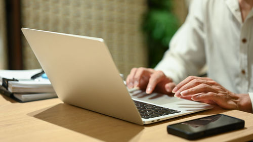 Midsection of woman using laptop on table