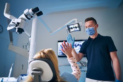 Dentist wearing surgical mask giving high-five to girl