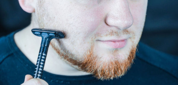 Close-up of man shaving beard at home