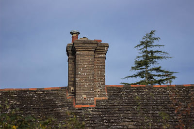 Low angle view of chimney on roof against sky