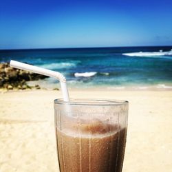 Close-up of drink on beach against sky