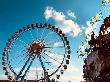 Low angle view of ferris wheel against cloudy sky