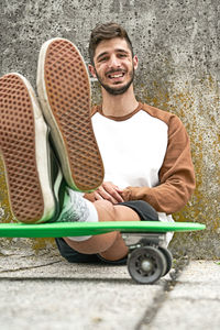 Young casual man sitting on skateboard person