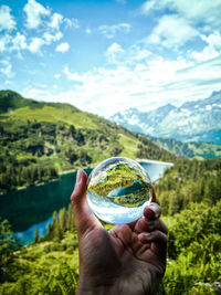 Lensball reflecting mountain range scene with lake and forest and mountains