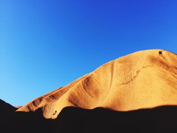 Low angle view of sand against clear blue sky