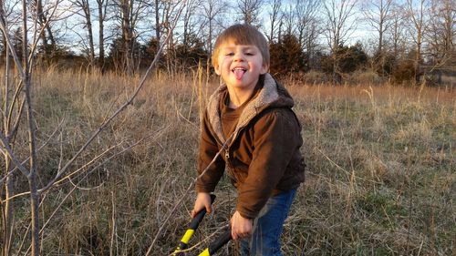 Portrait of playful boy sticking out tongue while standing on field