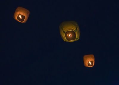 Low angle view of illuminated lamp against black background