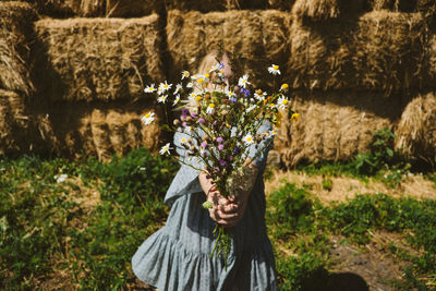 Midsection of person standing by flowering plants on field