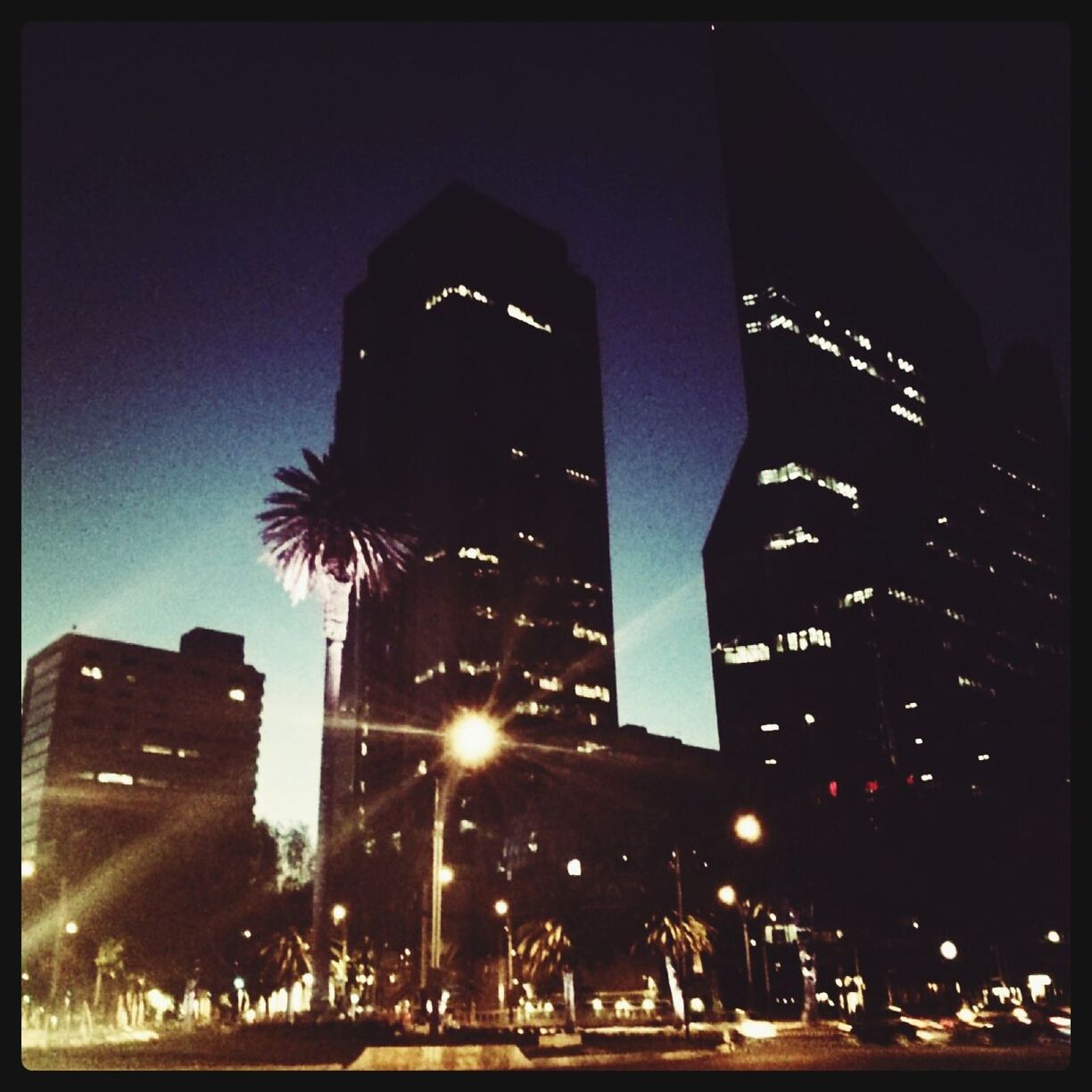 building exterior, illuminated, architecture, built structure, night, city, skyscraper, low angle view, tall - high, tower, street light, transfer print, clear sky, sky, city life, office building, auto post production filter, modern, city street, street