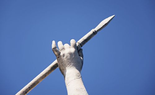 Sculpture of human hand holding spear