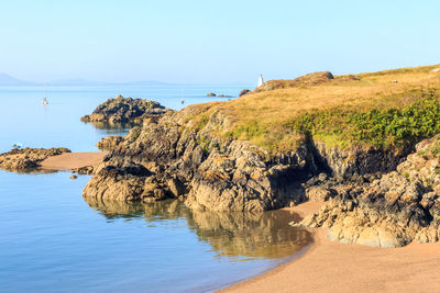 Scenic view of rocks by sea against sky