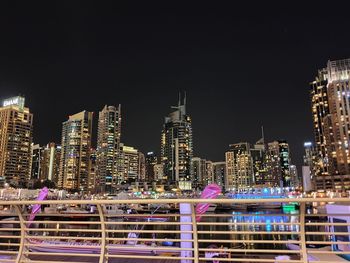 Illuminated modern buildings in city against sky at night