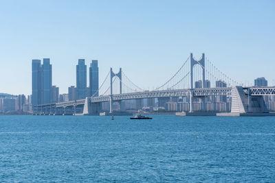 Suspension bridge over river against clear sky