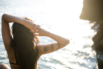 Young latina woman relaxing by the ocean at golden hour in summertime