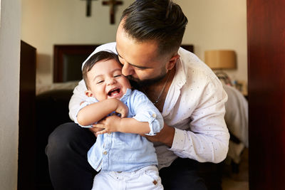 Delighted hispanic father having fun with adorable little kid while spending time together at home
