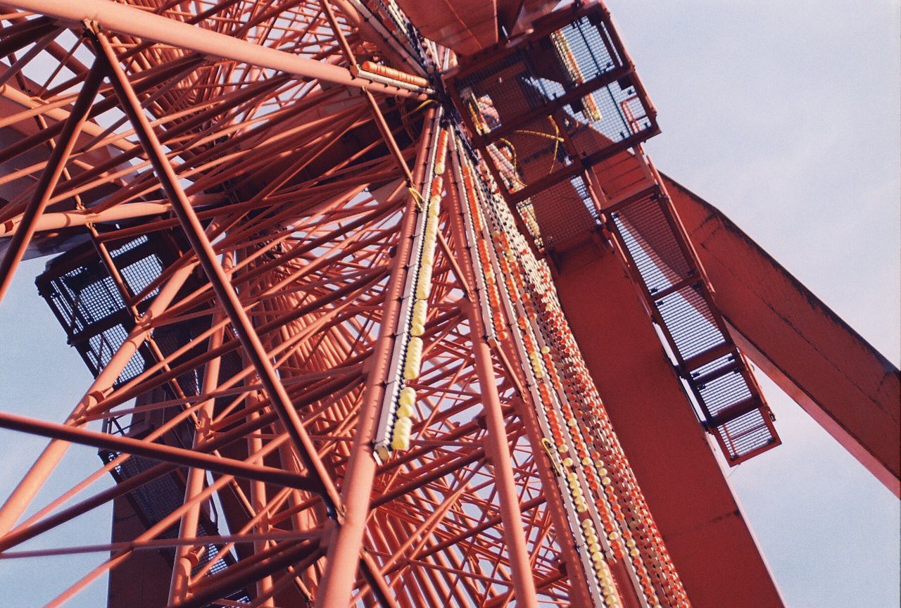 low angle view, built structure, architecture, metal, metallic, arts culture and entertainment, amusement park ride, amusement park, ferris wheel, sky, building exterior, red, clear sky, tower, no people, tall - high, day, outdoors, engineering, architectural feature