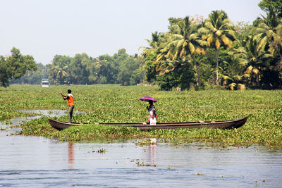 People rowing boat in river against sky