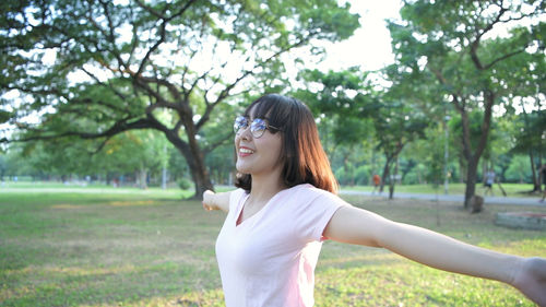 Young woman smiling while standing against trees