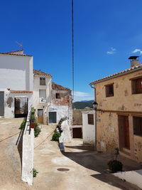 Street amidst buildings against blue sky