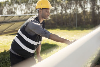 Young male engineer examining solar panels while working at power station