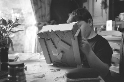 Boy making craft from cardboard box at table