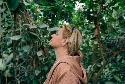 Side view of woman standing against plants