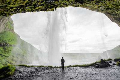 Rear view of man standing by waterfall